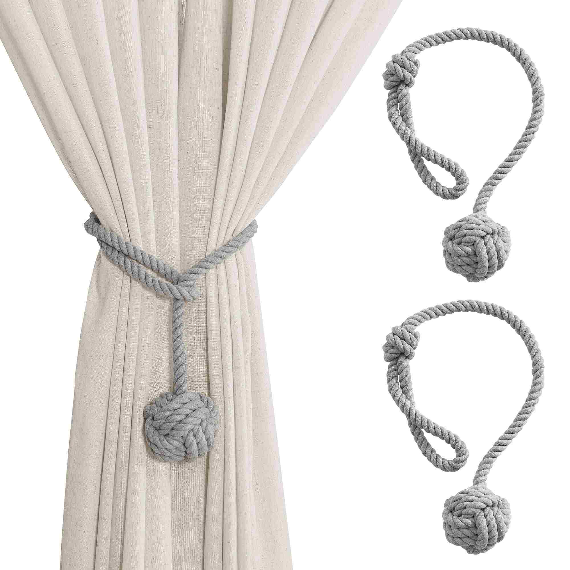 Gray macrame-style rope curtain tieback holding a beige outdoor curtain, with two standalone rope tiebacks featuring decorative knots.