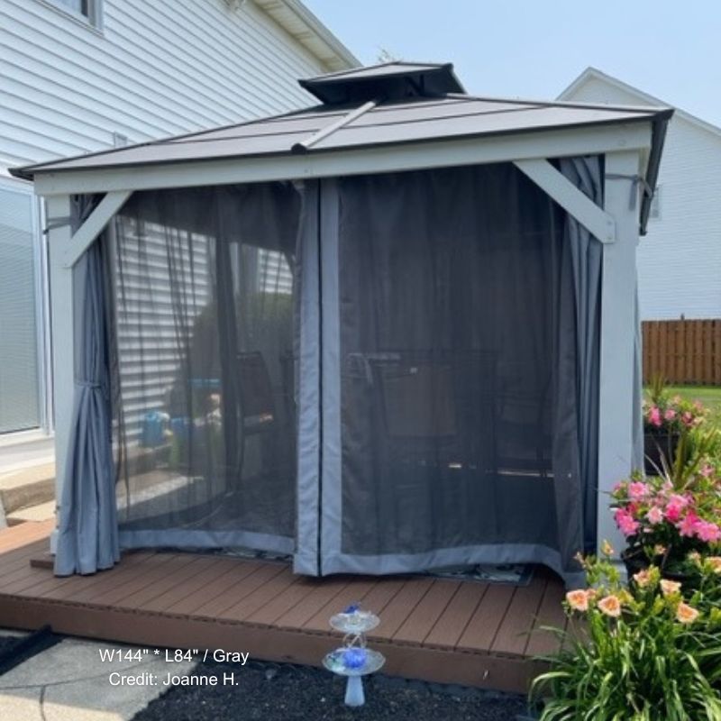 Weatherproof outdoor gazebo featuring zipped dark grey mosquito netting sidewall panels, one tied back, on a patio deck.