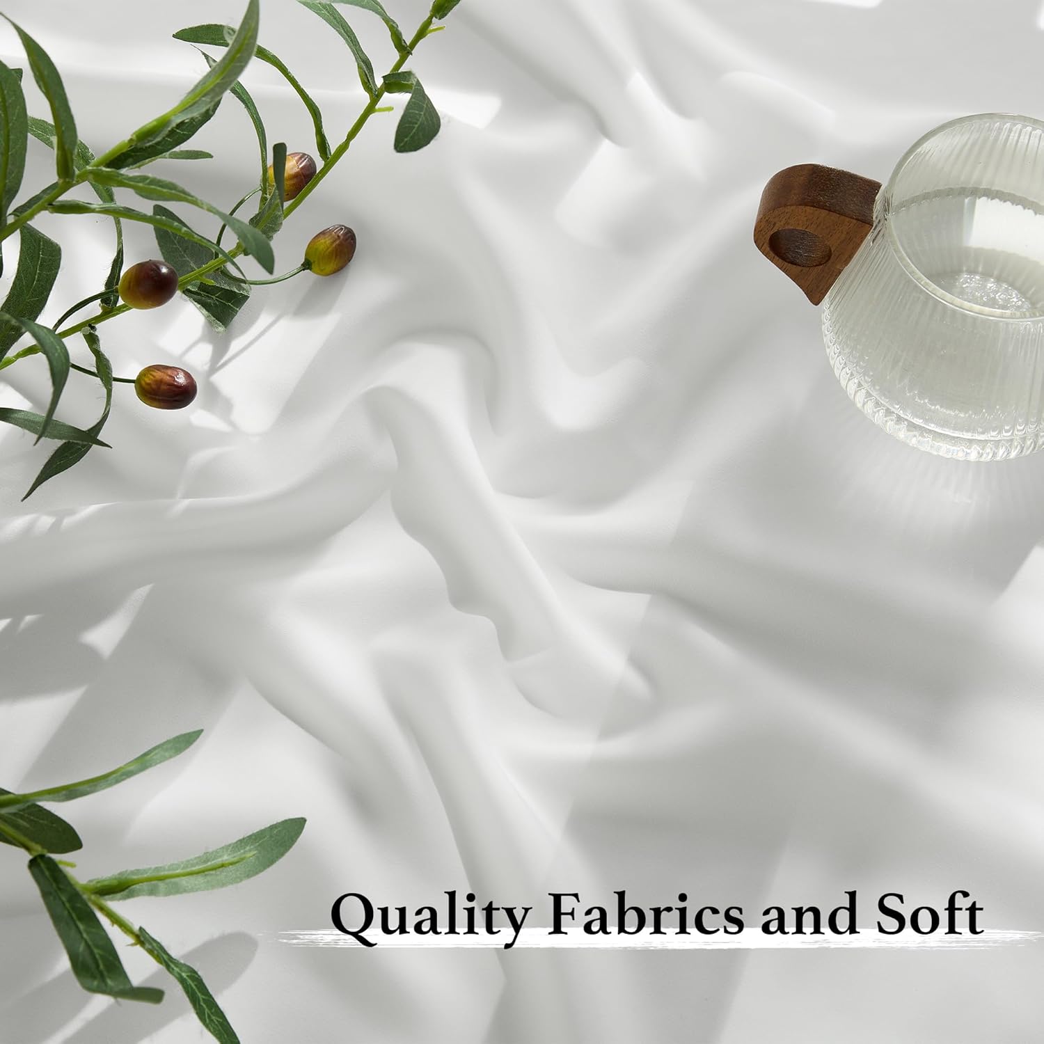 Close-up of white, soft, flowing waterproof outdoor sheer curtain fabric for patio, with a decorative olive branch and glass.