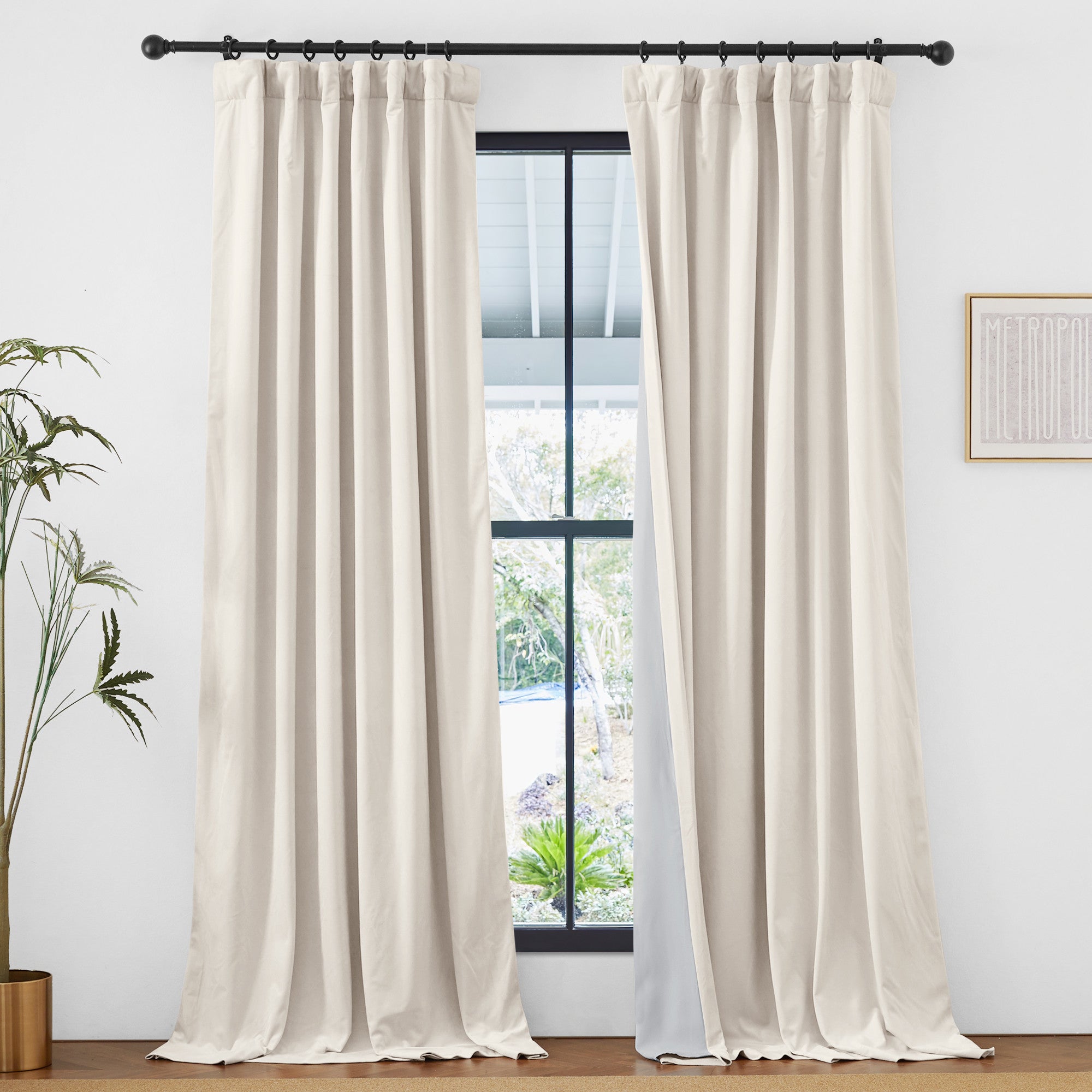 Off-white velvet thermal insulated light blocking drapes with rod pocket & back tab hang at a window, showing outdoor view.