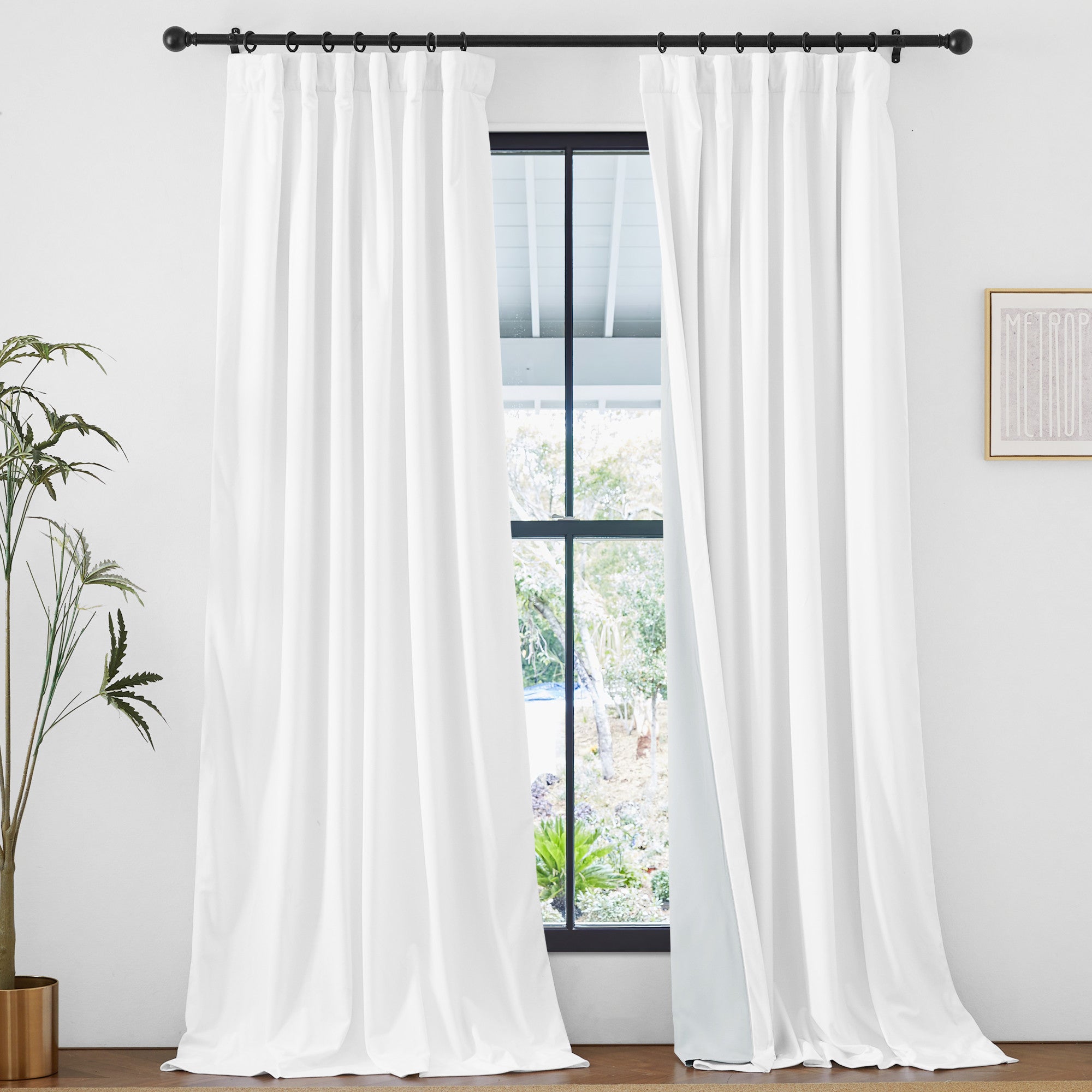 Thick white velvet thermal insulated light blocking drapes with rod pocket & back tab, hung on a black rod, framing an outdoor window view.