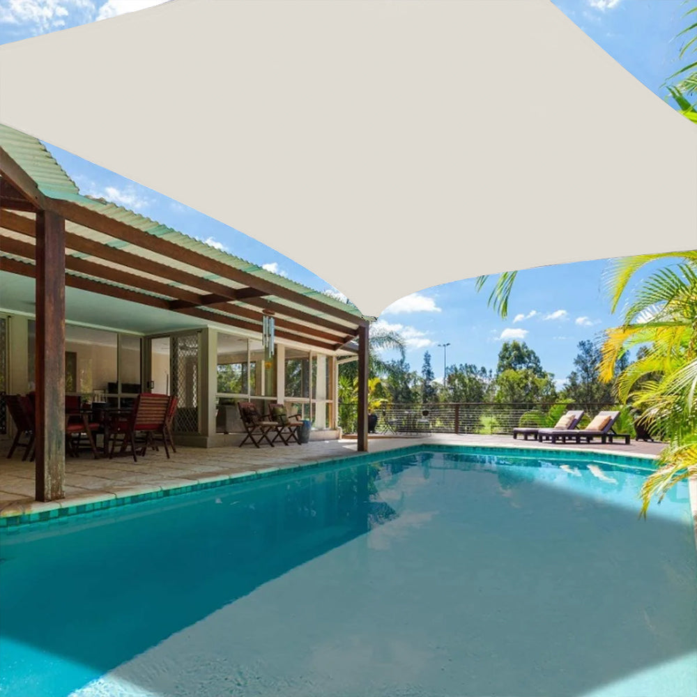 Opaque beige waterproof sun shade sail canopy over a luxurious patio dining area & swimming pool, offering UV protection.