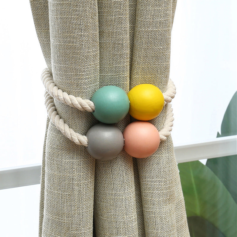 Stylish magnetic curtain holdback, hand-woven cotton rope with four colorful magnetic balls securing a textured outdoor curtain.