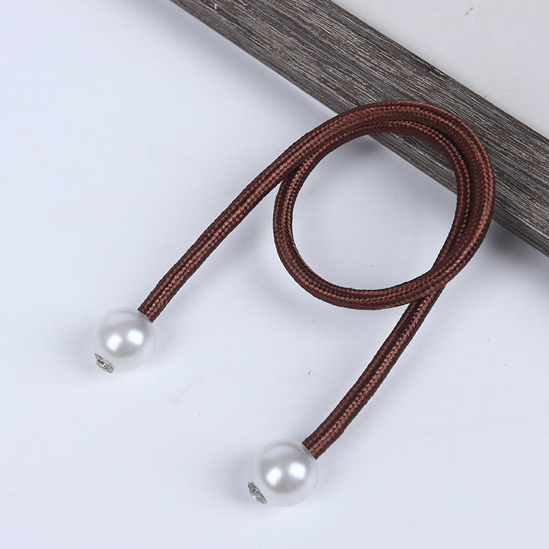Brown braided magnetic curtain tieback with two lustrous pearl balls on the ends for outdoor curtains.