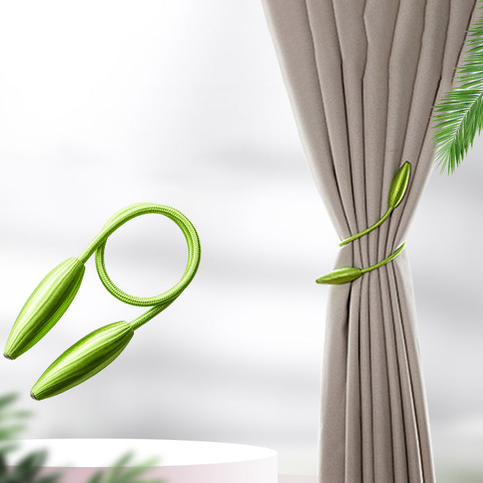 Decorative green leaf-design curtain tieback securing a beige pleated window curtain. Another simple modern curtain strap is displayed.