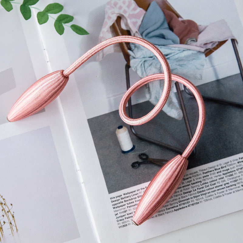 Rose gold flexible braided buckle curtain tieback strap, a modern decorative accessory with sleek oval ends for stylish curtains.