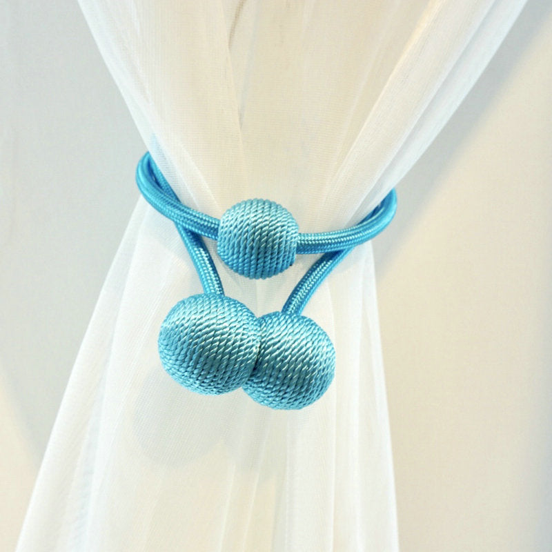 Modern light blue magnetic curtain tieback with woven sphere ends, elegantly securing a white sheer curtain, ideal for outdoor spaces.