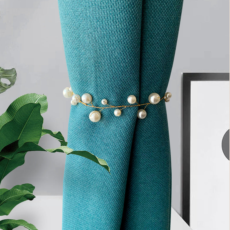 Stylish gold alloy pearl curtain tieback, featuring varied white pearls on a wire, cinching a textured teal curtain.