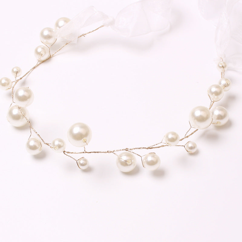 Elegant alloy pearl curtain tieback with varying size lustrous white pearls on wire, secured by sheer white ribbons for decorative styling.