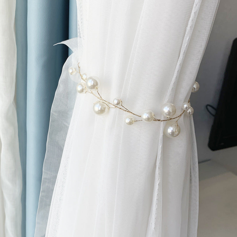 Elegant alloy pearl curtain tieback holding back a white sheer curtain, featuring gold-tone wire with varying sizes of white pearls.