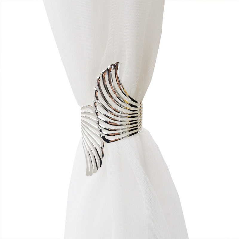 Sleek silver angel wings curtain tieback holding a gathered sheer white outdoor curtain, perfect for patio or pergola.