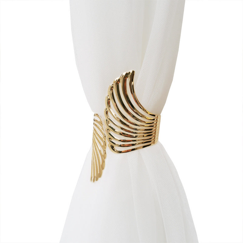 Gold angel wings curtain tieback securing a sheer white curtain