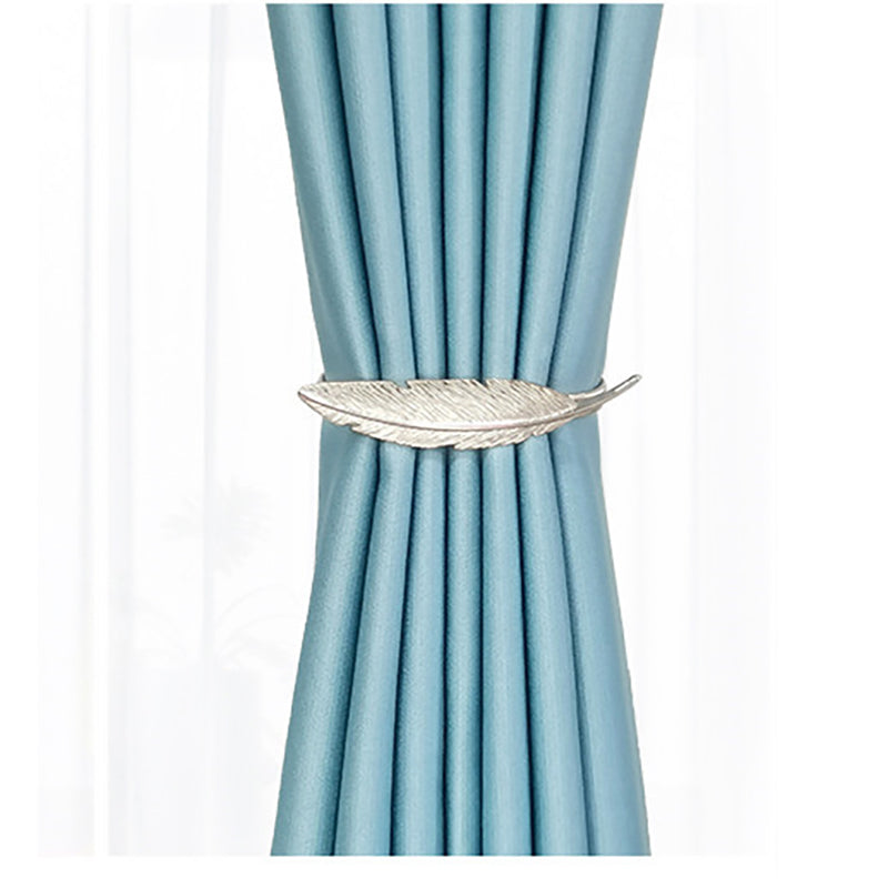 Silver feather design metal curtain tieback elegantly securing a pleated light blue curtain, perfect for stylish outdoor spaces.