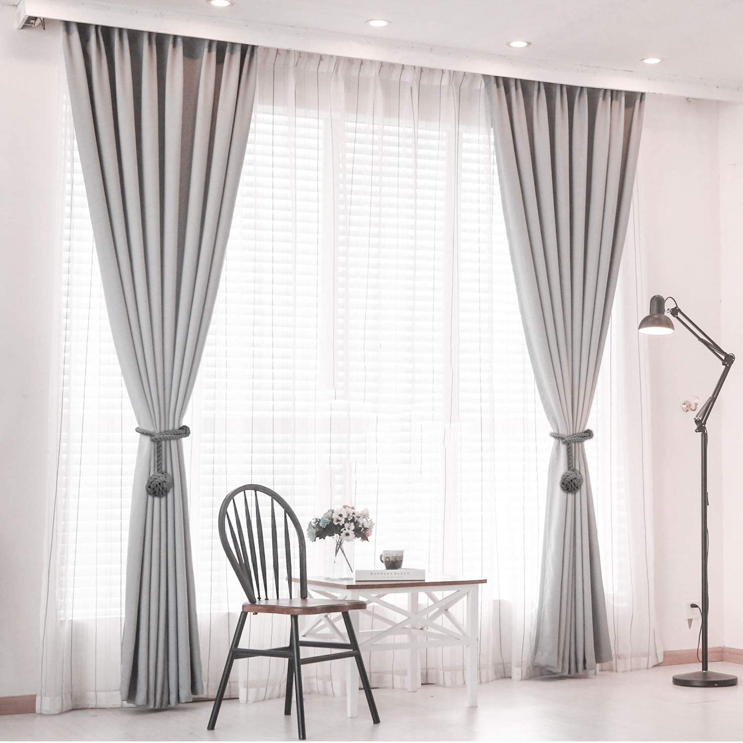 Stylish grey macrame rope curtain tiebacks securing two light-colored curtains in a contemporary room, enhancing window decor.