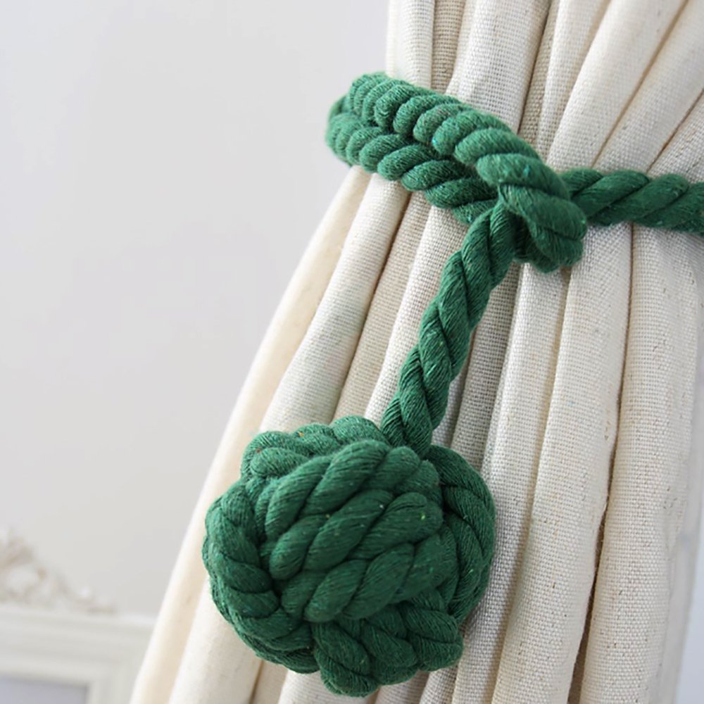 Stylish green macrame rope curtain tieback with an intricate knot, holding back a pleated cream outdoor curtain.