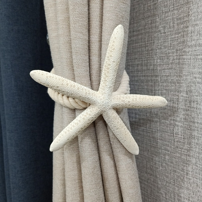Natural white starfish and rope curtain tieback securing a beige outdoor curtain, adding coastal decor to your space.