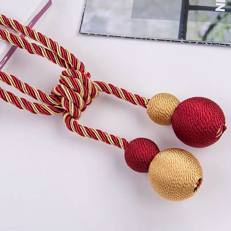Elegant red and gold twisted rope magnetic ball tie back, a stylish curtain accessory for window treatments.