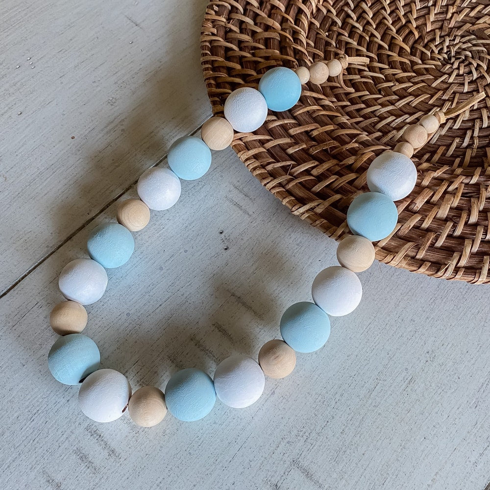 Wooden bead curtain tieback with blue, white, and natural beads. Ideal decorative strap for outdoor curtains & patio drapes.