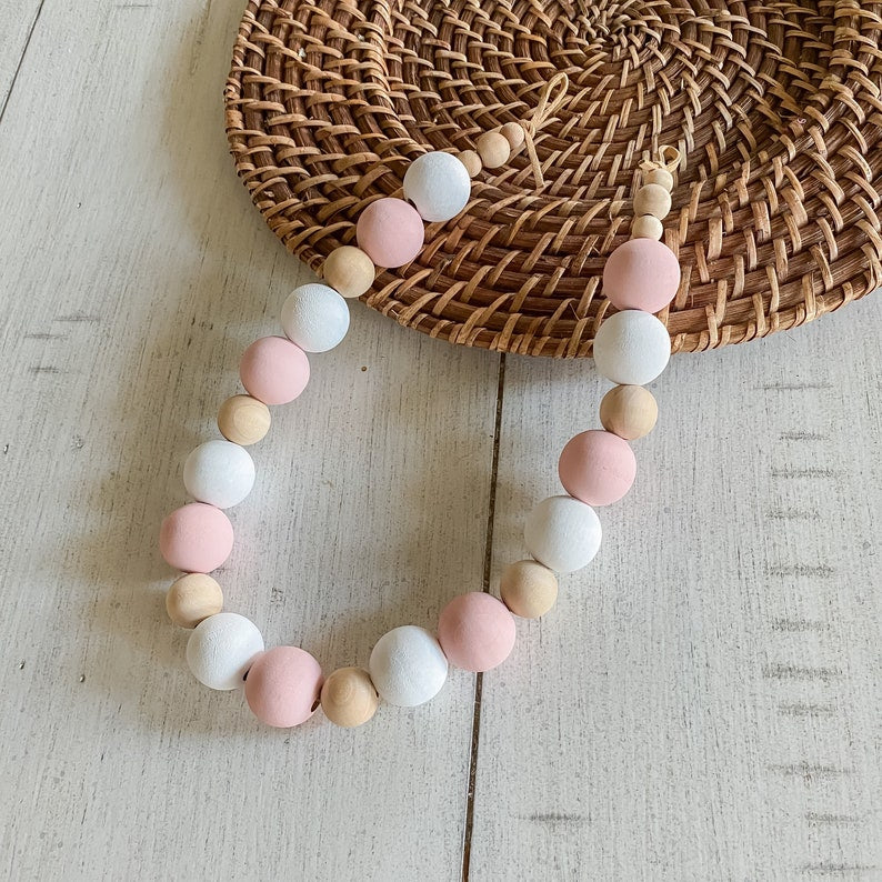 Chic wooden bead curtain tieback with alternating pink, white, and natural wood beads, perfect for stylish outdoor curtains.