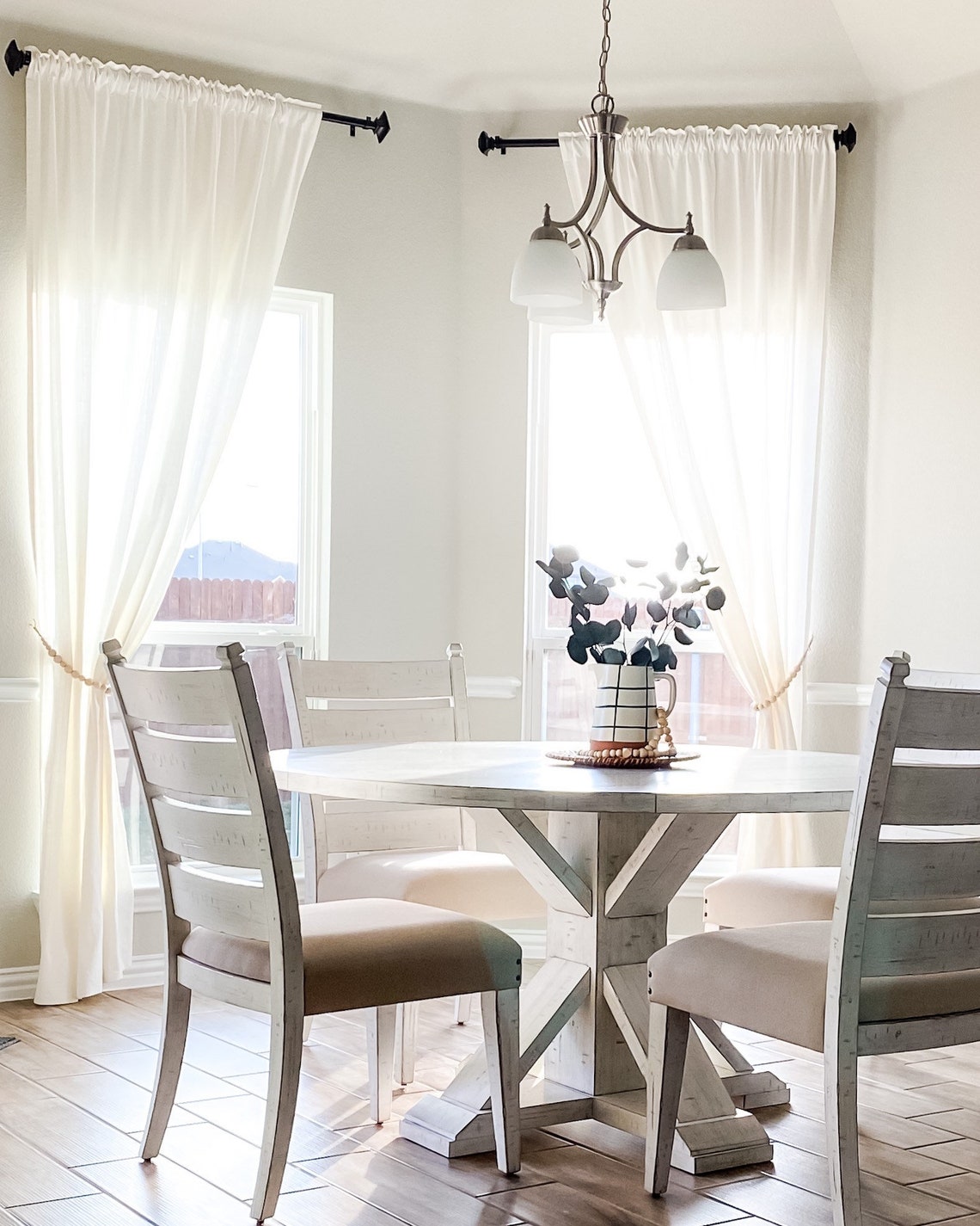 Natural wooden beads curtain straps tieback holding back a white sheer panel in a bright, modern dining space