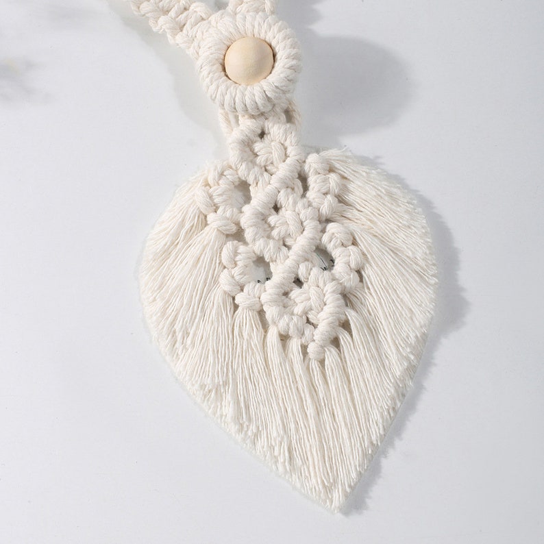 White macrame leaf curtain tieback, showcasing woven texture & wooden bead. Perfect for outdoor patio or garden curtain decor.