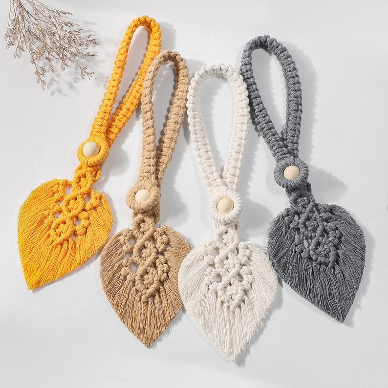 Set of four decorative macrame leaf curtain tiebacks in yellow, tan, white, and grey with wooden beads, for outdoor curtains.