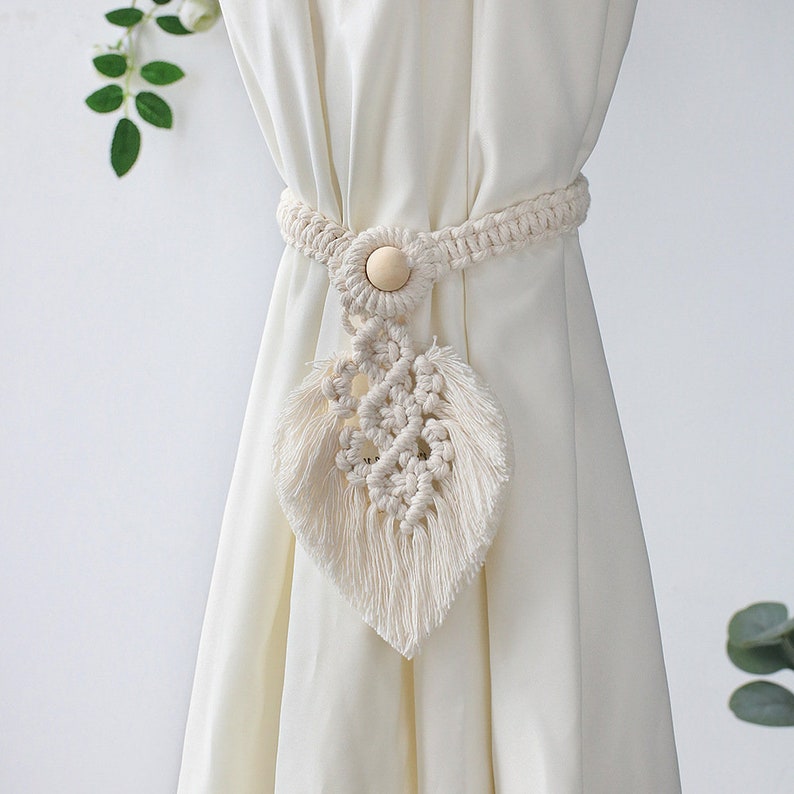 Stylish macrame leaf curtain tieback with wooden bead accent holding back a weatherproof cream outdoor curtain.