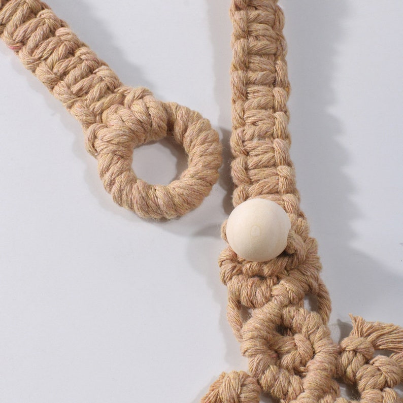 Natural beige macrame outdoor curtain tieback detail, highlighting woven loop and round wooden bead closure.