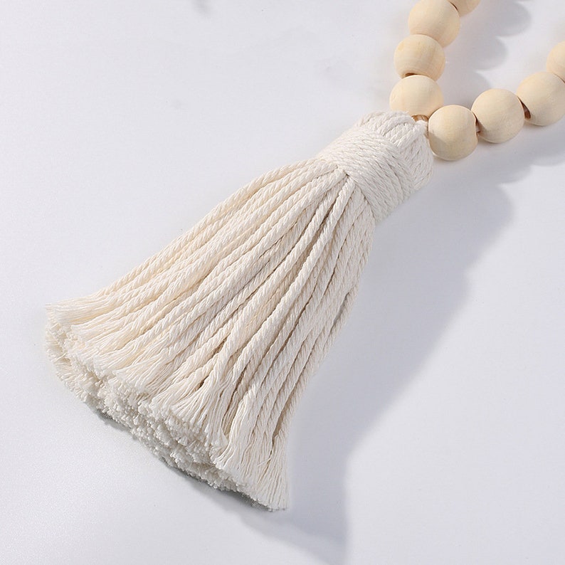 Close-up of a natural macrame tassel curtain tieback with light wooden beads, perfect for outdoor patio curtains.
