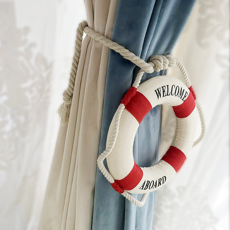Nautical rope curtain tieback for outdoor curtains, featuring a decorative lifebuoy with Welcome Aboard.