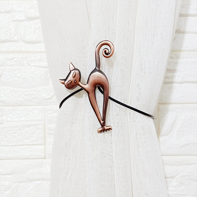 Decorative bronze cat magnetic curtain tieback holding back a white curtain, enhancing interior window styling.
