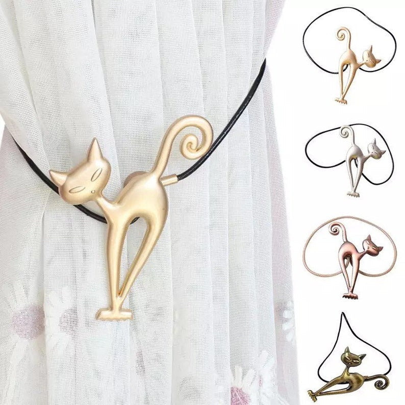 Decorative gold cat magnetic curtain tieback holding back a pleated white curtain. Also showing silver, rose gold, & bronze styles.