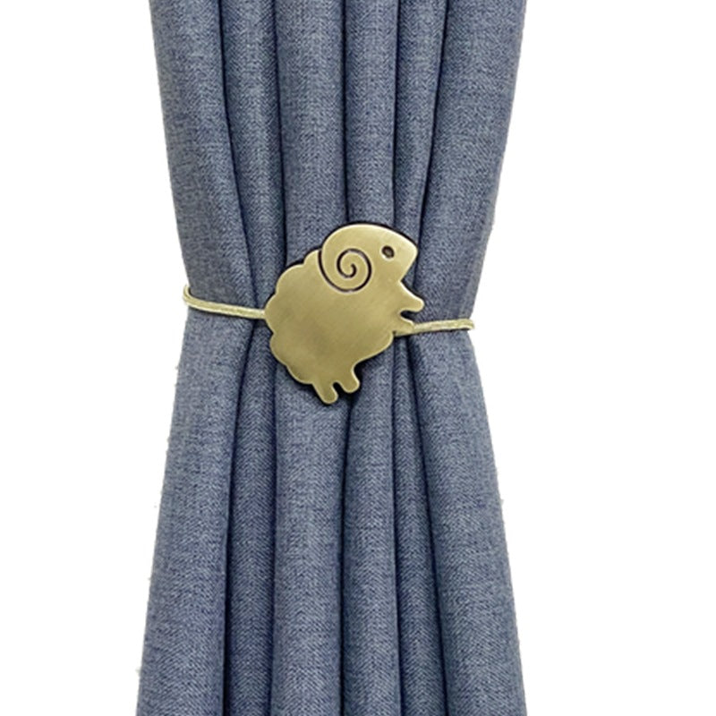 Cute gold sheep magnetic curtain tieback with spiral detail, cinching a blue pleated outdoor curtain.
