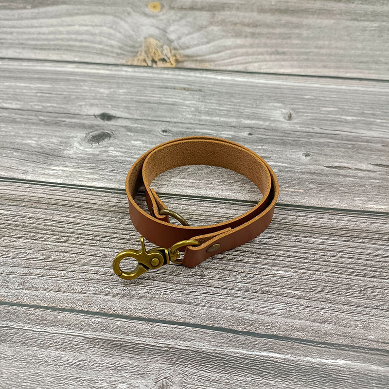 Brown leather curtain strap tieback accessory with antique brass-tone snap hook, ideal for outdoor curtains.