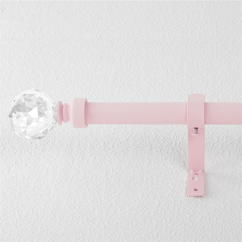 Pink window outdoor curtain rod with a clear crystal ball finial and mounting bracket against a white wall.