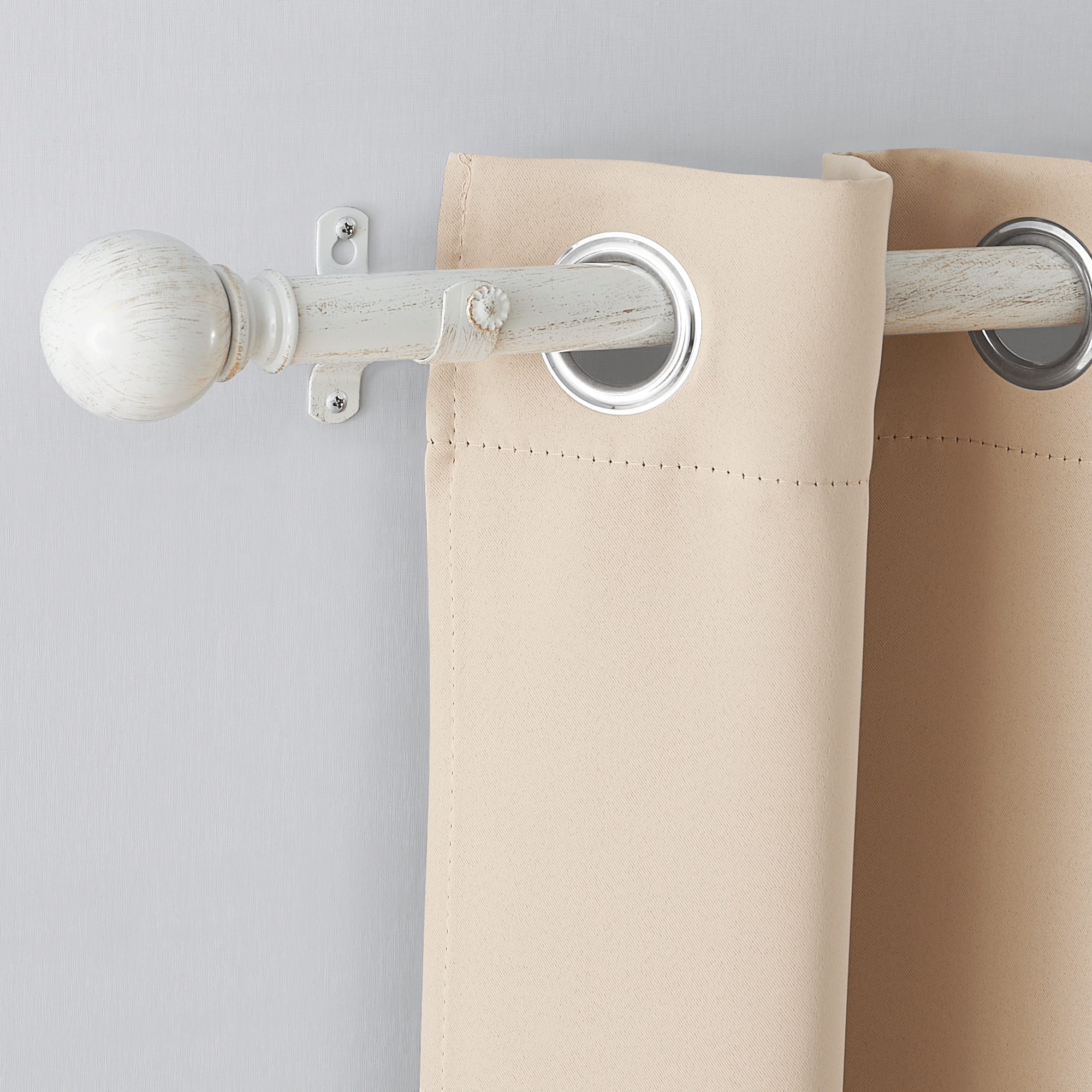 Antique white decorative outdoor/indoor curtain rod with ball finial, holding a beige grommet top curtain.