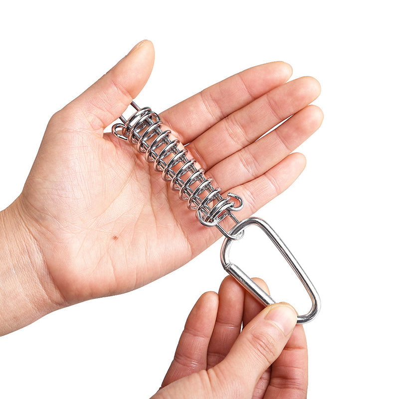 Hand holding a silver metal spring with a carabiner clip, used as an awning fixed buckle for outdoor canopy tents.