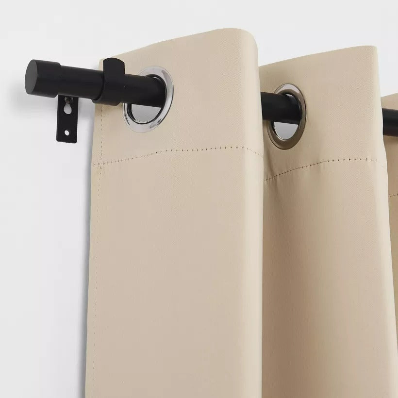 Black cylindrical finial and heavy-duty indoor/outdoor curtain rod holding beige weatherproof grommet curtains.