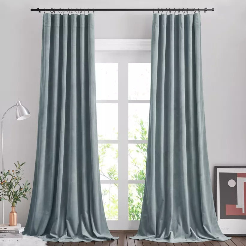 Black brushed finial indoor/outdoor curtain rod displaying pleated light blue drapes in a sunlit living room.