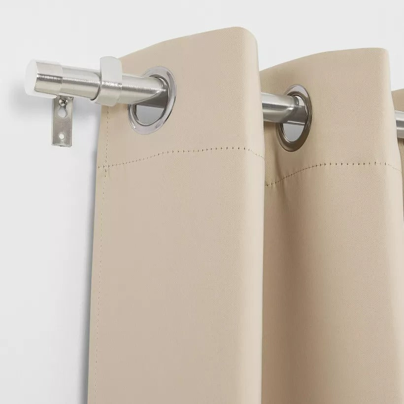 Brushed finial silver indoor/outdoor curtain rod mounted on a wall, holding a beige grommet patio curtain.