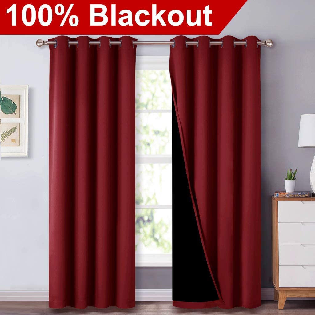 Two red double layer grommet blackout curtains hung on a rod, one panel revealing the dark inner lining for effective room darkening.