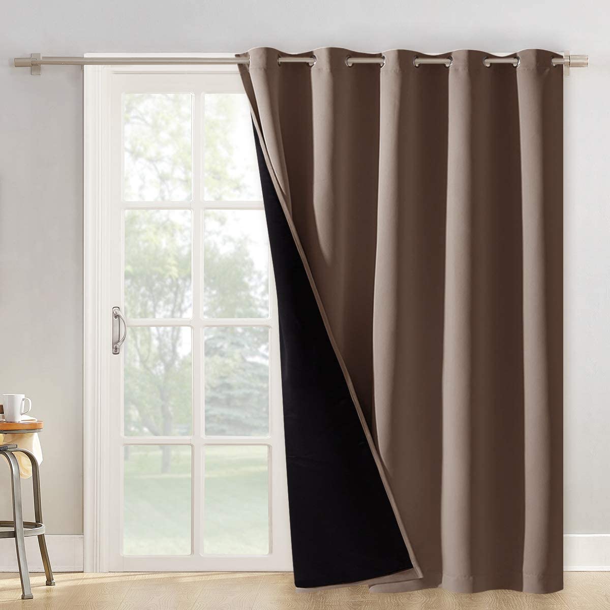 Single brown double layer blackout curtain panel with silver grommets partially open on a rod, revealing black noise-reducing lining for patio door.