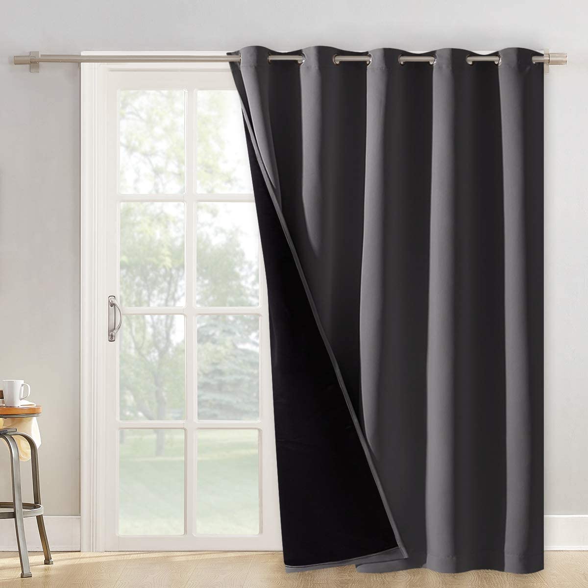 Charcoal gray double layer grommet blackout curtain panel partially open, revealing its black inner noise reducing layer for a patio door.