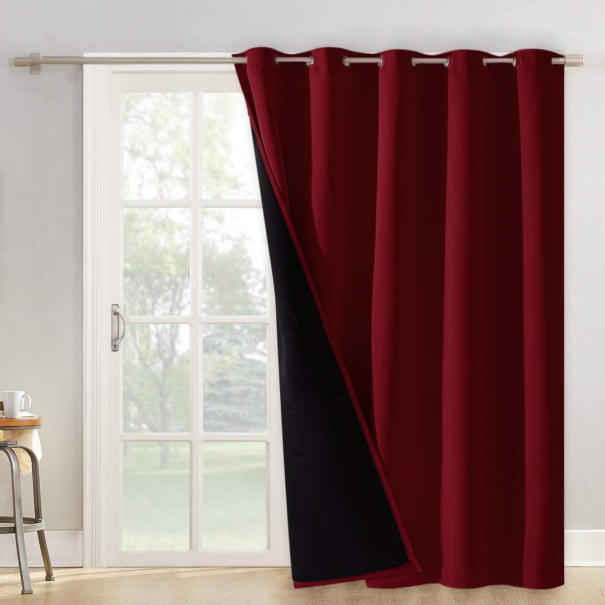Double layer red blackout curtain panel with grommets and black backing partially covering a living room window