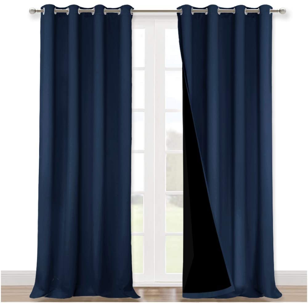 Two navy blue double layer noise reducing curtains with silver grommets for a living room, slightly open revealing blackout lining.