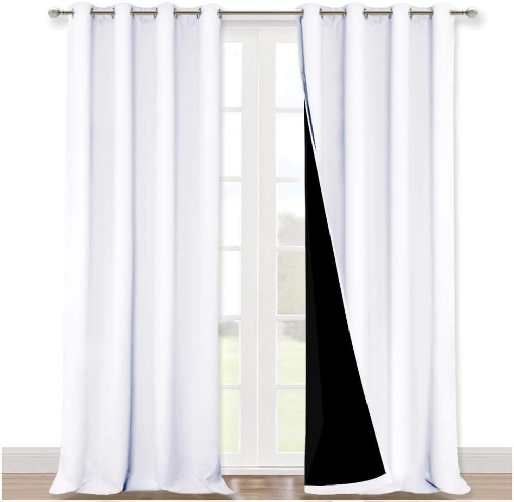 White double layer noise reducing curtains with silver grommets for living room, one panel drawn back revealing black insulating layer.
