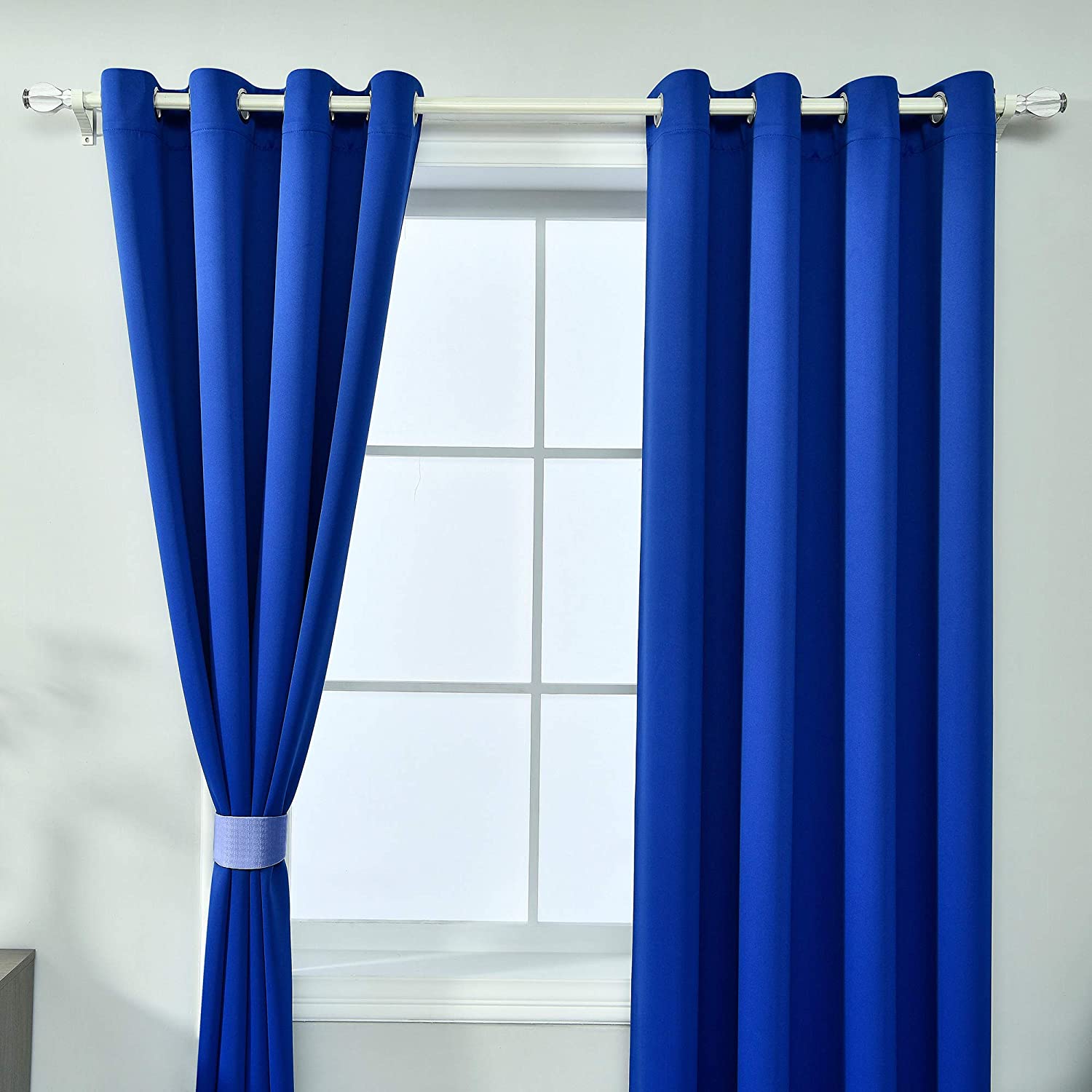 Deep blue grommet blackout thermal insulated curtains, two panels, one tied back revealing a window, ideal for living room/bedroom.