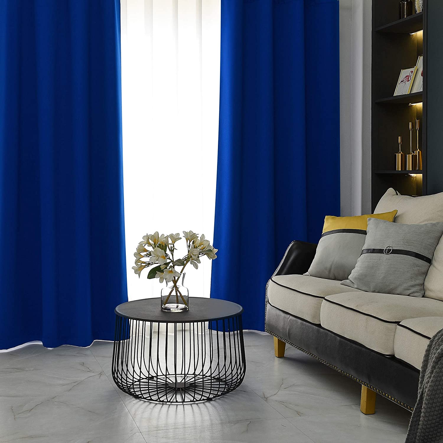 Two royal blue grommet blackout thermal insulated curtains framing a window in a modern living room, perfect for bedrooms.
