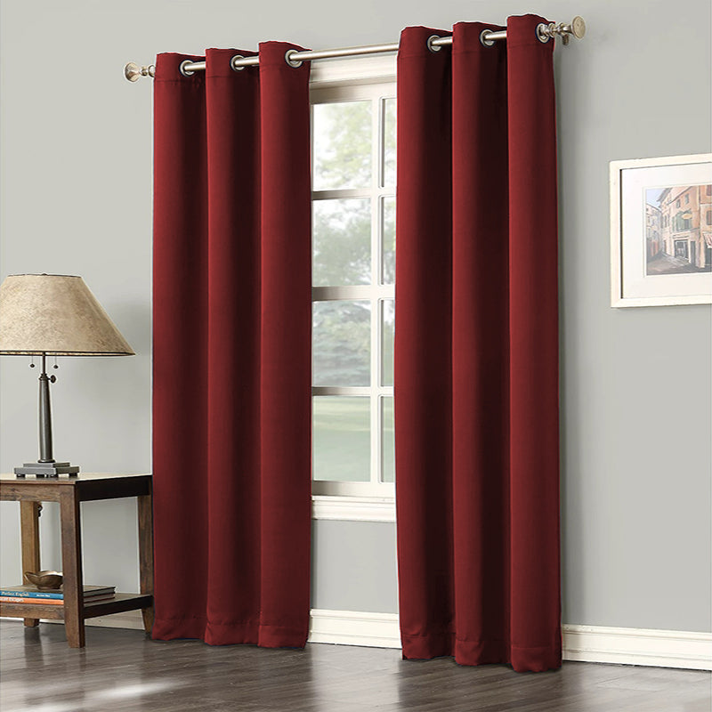 Two deep red grommet blackout curtain panels for living room or bedroom. Noise reducing drapes on a window rod.