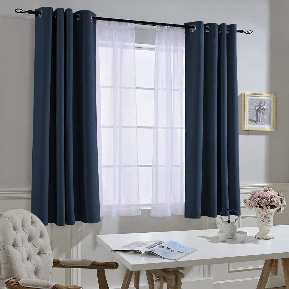 Two dark blue grommet blackout curtains with white sheer panels for a living room or bedroom window. Noise reducing privacy window treatment.
